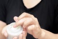 Female hands holding and apply jar of nourishing cream on white background.Skin care and beauty concept.Closeup