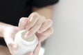 Female hands holding and apply jar of nourishing cream on white background.Skin care and beauty concept.Closeup