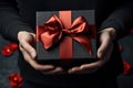 female hands holding a black gift box with a red bow made of satin ribbon, Generative AI Royalty Free Stock Photo