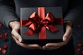 female hands holding a black gift box with a red bow made of satin ribbon, Generative AI Royalty Free Stock Photo