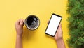 Female hands holding black mobile phone with blank white screen and mug of coffee. Mockup image with copy space. Top view banner Royalty Free Stock Photo