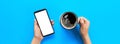 Female hands holding black mobile phone with blank white screen and mug of coffee. Mockup image with copy space for you design. Royalty Free Stock Photo