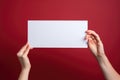 Female hands holding a blank sheet of paper on a red background, Empty card in woman hand. Copy space. American flag background, Royalty Free Stock Photo