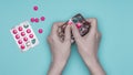 Female hands holding blister pack with pink pills over pastel blue background. Sick patient taking medication. Royalty Free Stock Photo