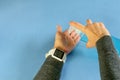 Female hands holding bottle of antibacterial liquid gel sanitizer over the blue background. Wrist watch with empty indicator