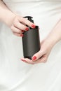Female hands holding a bottle of cosmetic product or liquid soap. unbranded black bottle in woman& x27;s hand. fresh red Royalty Free Stock Photo