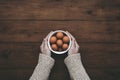 Female hands holding bowl of brown eggs on wooden table Royalty Free Stock Photo