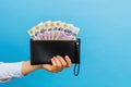 Female hands holding british pounds banknotes in black wallet on a blue background