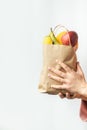 Female hands holding brown paper bag full of fruits on the white background. Food shopping and delivery concept. Healthy nutrition Royalty Free Stock Photo