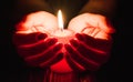 Female hands holding a burning candle in the dark Royalty Free Stock Photo