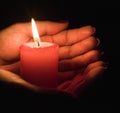 Female hands holding a burning candle in the dark Royalty Free Stock Photo