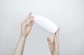 Female hands holding a can of shampoo with a blank label. White background, space for text. Composition of shampoo or conditioner Royalty Free Stock Photo
