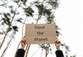 Female hands holding cardboard with text SAVE THE PLANET outdoors. Nature background. Protester activist