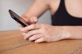 Female hands holding cell phone and a cup of coofee on the wooden table