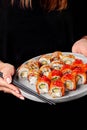 Female hands holding chopsticks and plate with sushi rolls with salmon and eel Royalty Free Stock Photo