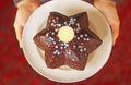 Female hands holding a christmas cake in star shape with a candle