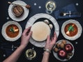 Female hands holding Christmas Eve wafers. Table with Christmas dinner for two Royalty Free Stock Photo