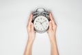 Female hands holding clock on white paper. Royalty Free Stock Photo