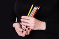 Female hands holding colored pencils on a black background. Manicure with black nail polish. Copy space Royalty Free Stock Photo