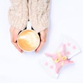 Female hands holding cup of cappuccino. Gift alike dessert with