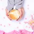 Female hands holding cup of cappuccino. Gift alike dessert with