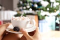 Female hands holding a cup of hot chocolate with marshmallows.