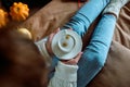 Female hands holding a cup of hot tea or coffee, autumn flat, with yellow leaves, cozy knitwear, blank for the designer Royalty Free Stock Photo