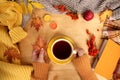 Female hands holding a cup of hot tea or coffee, flat in the Scandinavian hugg style, with yellow leaves, cozy knitwear, candles Royalty Free Stock Photo