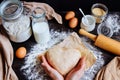 Female hands holding dough in heart shape top view. Baking ingredients on the dark wooden table