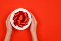 Female hands holding a festive box with ribbons and bows. Red festive background top horizontal view copyspace Royalty Free Stock Photo