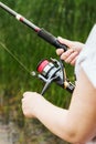 Female hands holding a fishing rod and twist the handle Royalty Free Stock Photo