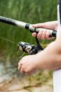 Female hands holding a fishing rod and twist the handle Royalty Free Stock Photo