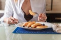 Female hands holding fork and knife. Woman eating cottage cheese pankaces or traditional syrniki with blueberries and honey.