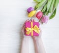 Female hands holding a gift box spring birthday , romantic a bouquet of tulips on a wooden background Royalty Free Stock Photo
