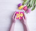 Female hands holding a gift box anniversary birthday , romantic a bouquet of tulips on a wooden background Royalty Free Stock Photo