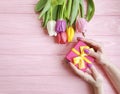 Female hands holding a gift box spring   present birthday , romantic  a bouquet of tulips on a wooden background Royalty Free Stock Photo