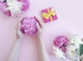Female hands holding a gift box birthday decoration celebration bouquet peony flower on a colored background Royalty Free Stock Photo