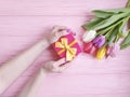 Female hands holding a gift box, romantic  a bouquet of tulips on a wooden background Royalty Free Stock Photo