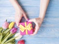 Female hands holding a gift box, spring celebration romance a bouquet of tulips on a blue wooden background Royalty Free Stock Photo