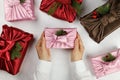 Female hands holding a gift. Japanese wrapping cloth Furoshiki. Silk pink cloth with green fir and pine cones.