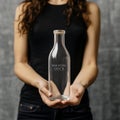 Female hands holding glass bottle mockup without label