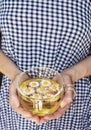 Female hands holding a glass cup with chamomile tea and chamomile flowers inside against the background of a blue-white checkered Royalty Free Stock Photo