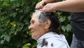 Cutting senior woman hair at backyard while staying home at quarantine