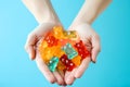 Female hands holding a handful of Multi-colored cbd gummy bears on a blue background. View from above Royalty Free Stock Photo