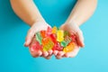 Female hands holding a handful of Multi-colored cbd gummy bears on a blue background. View from above Royalty Free Stock Photo