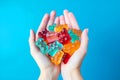 Female hands holding a handful of Multi-colored cbd gummy bears on a blue background. View from above Royalty Free Stock Photo