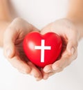 Female hands holding heart with cross symbol Royalty Free Stock Photo