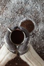 Female hands holding hot coffee above wooden table. Top view wit