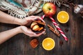 Female hands holding a hot mulled wine with spices, apple and orange on wood Royalty Free Stock Photo