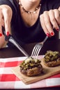 Female hands holding knife and fork and cutting meal. Mushrooms with cheese on a tablecloth. Appetizer. Food background Royalty Free Stock Photo